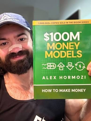 Alex Hormozi holding the $100M Money Models book